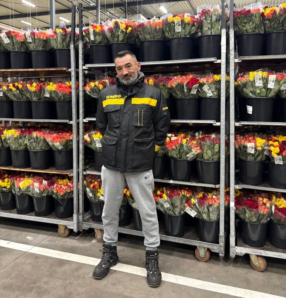 man voor rek vol met bloemen